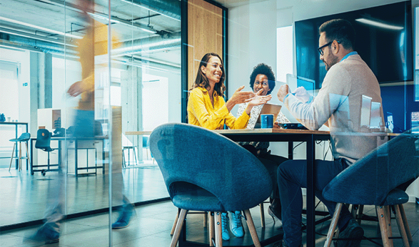 Group-of-professionals-at-meeting Team of professionals in meeting room smiling while talking.